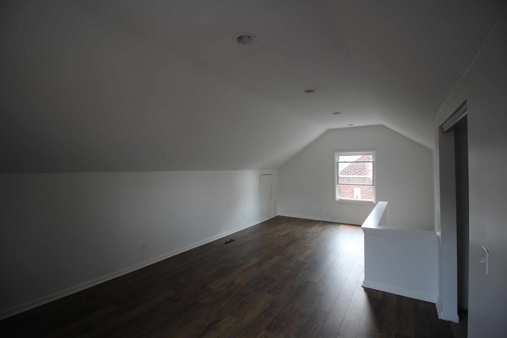a room with white walls and wood floors and a window