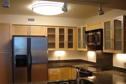 A kitchen with a refrigerator, microwave, and cabinets.