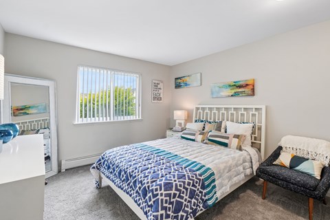 A bedroom with a bed, chair, and window.