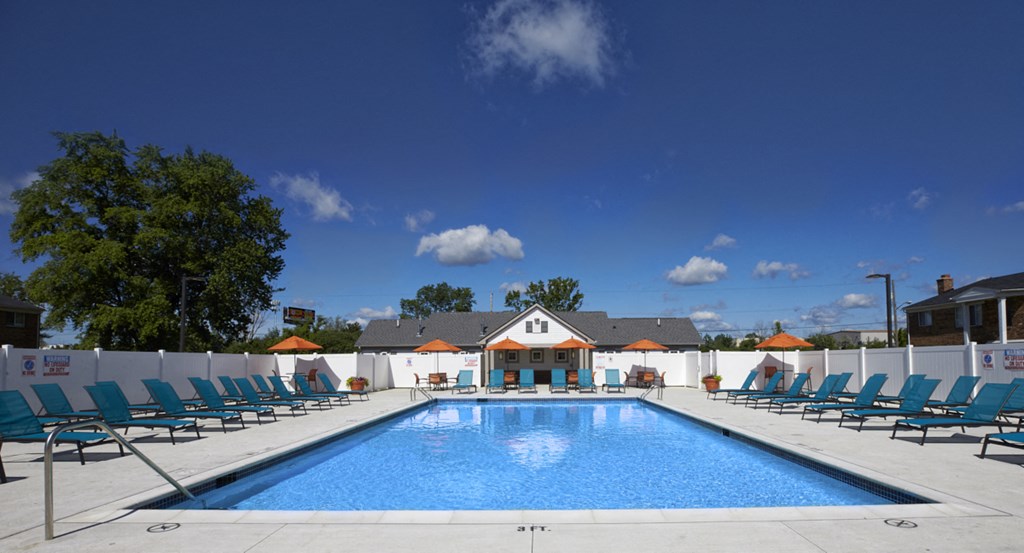 A large swimming pool surrounded by lounge chairs and umbrellas.