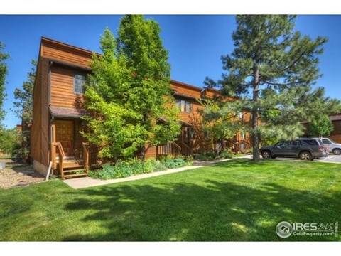 a large wooden house with a green lawn and trees