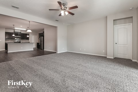 A spacious room with a ceiling fan and a carpeted floor.