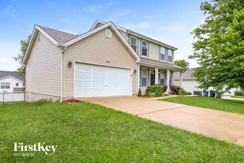 a beige house with a white garage door and a driveway