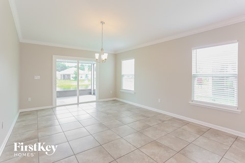 A spacious room with a tile floor and a chandelier hanging from the ceiling.