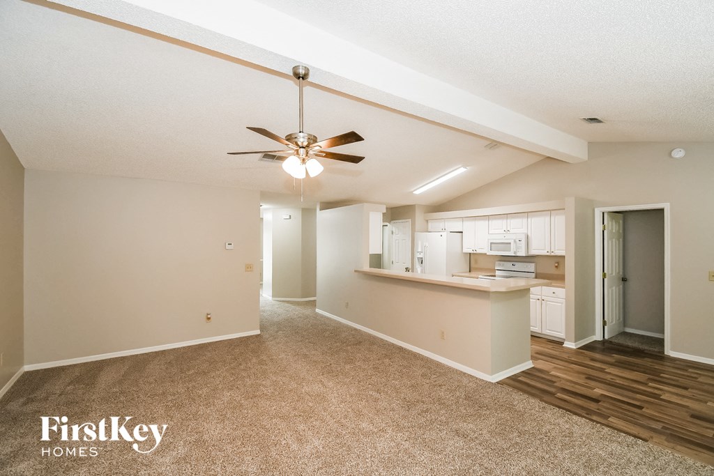 A spacious room with a ceiling fan and a carpeted floor.