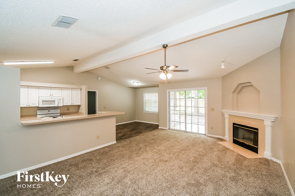 A spacious living room with a fireplace and a ceiling fan.