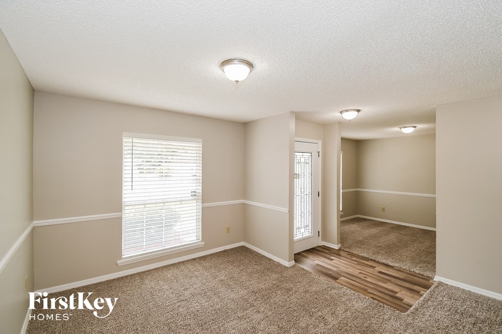A room with a carpeted floor and a door leading to another room.