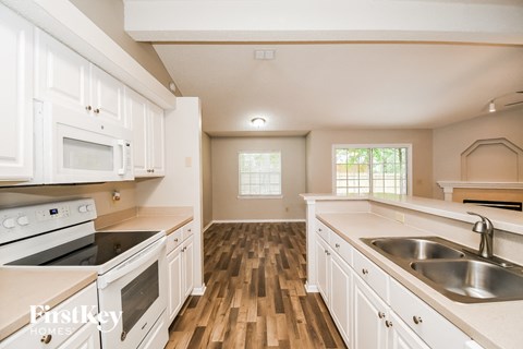A kitchen with white cabinets and a wooden floor.