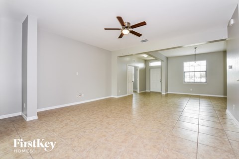 an empty living room with a ceiling fan