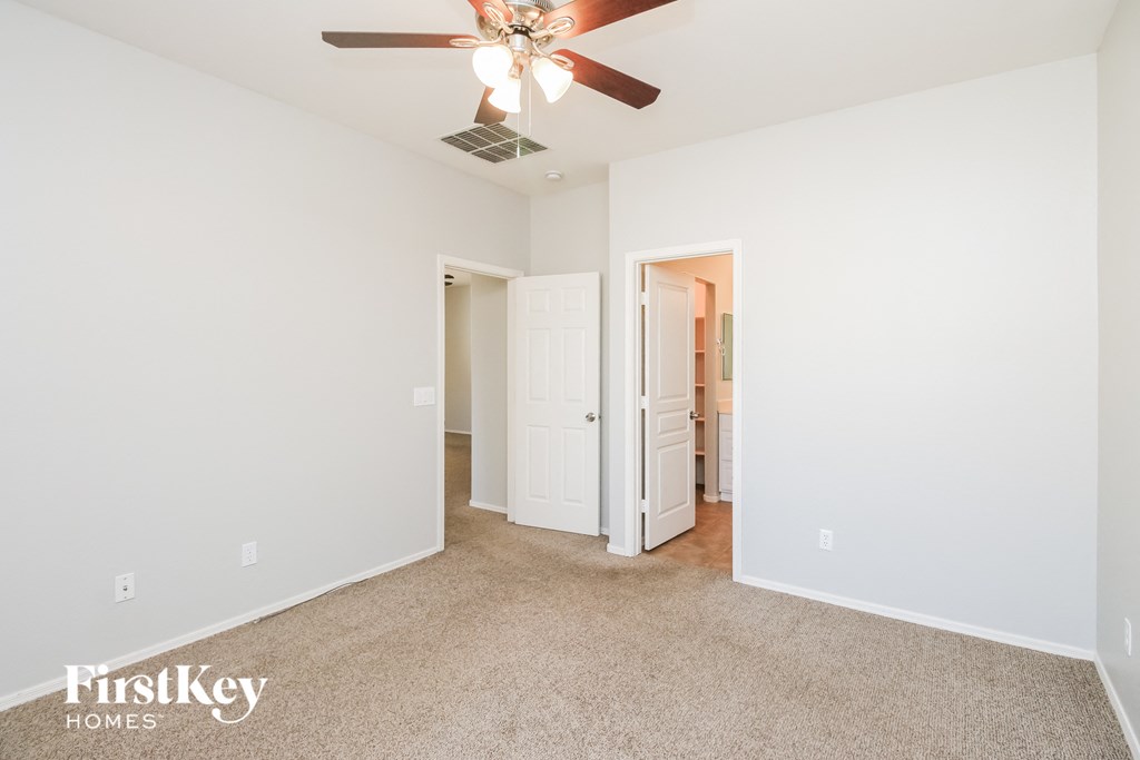 a bedroom with white walls and a ceiling fan