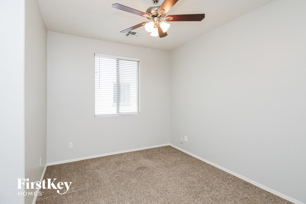 a bedroom with white walls and a ceiling fan