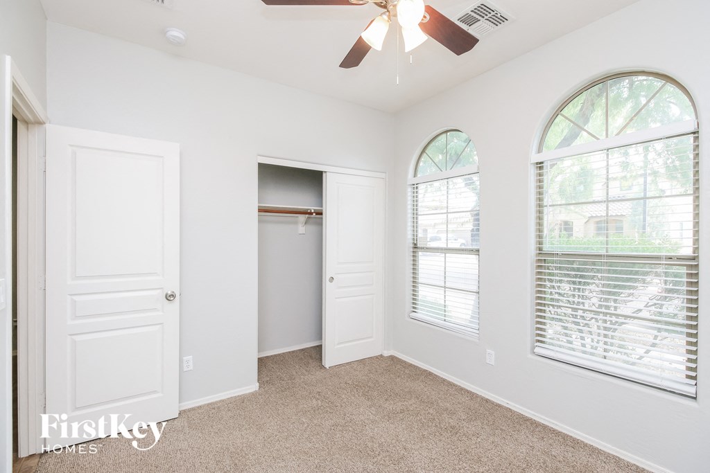 a bedroom with two windows and a closet and a ceiling fan