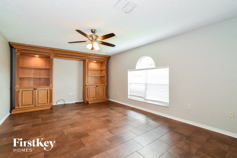 a empty living room with a ceiling fan and a window