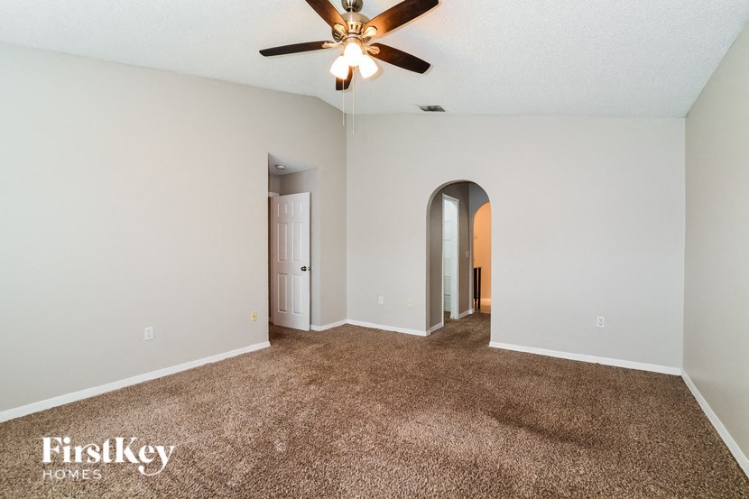 a living room with carpet and a ceiling fan