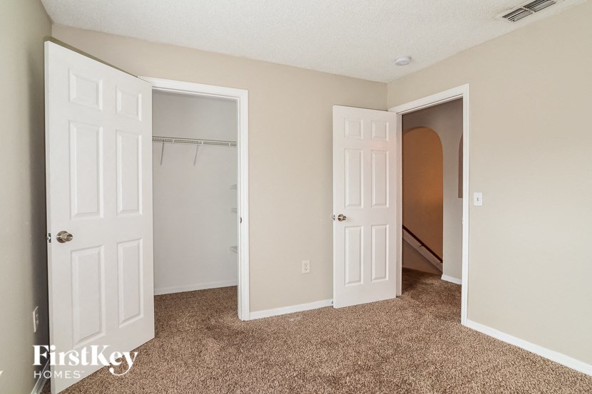 an empty bedroom with two doors and a closet