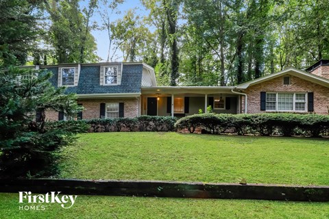 A house with a green lawn and trees in the background.