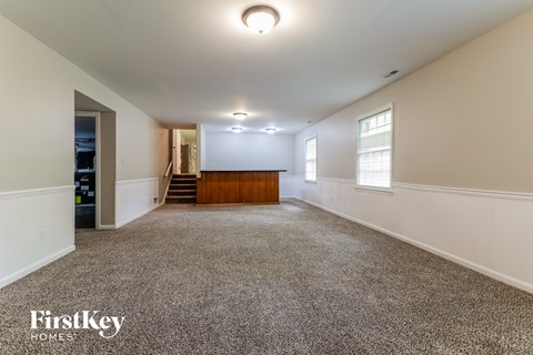 A spacious room with a carpeted floor and a wooden door at the end.