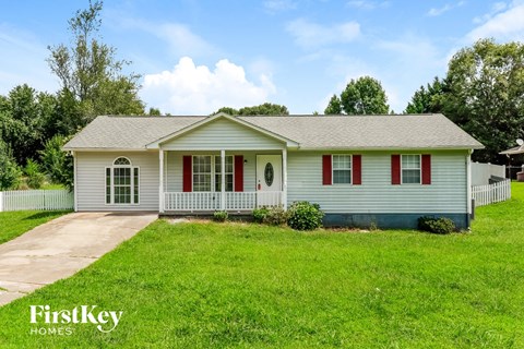a small white house with red shutters and a lawn
