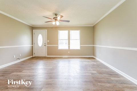 an empty living room with white walls and a ceiling fan