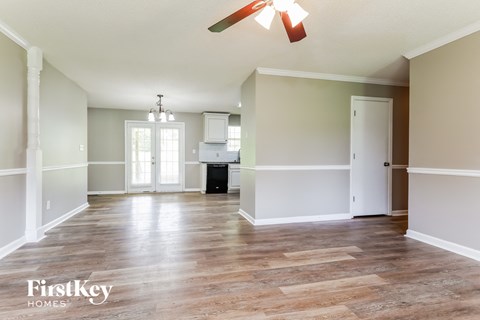an empty living room with a ceiling fan and a kitchen