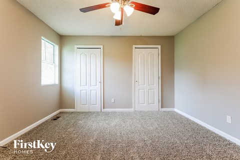 the master bedroom has a carpeted floor and a ceiling fan