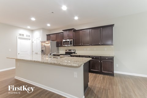 A kitchen with a granite countertop and wooden cabinets.