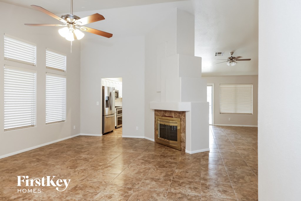 A spacious living room with a fireplace and a ceiling fan.