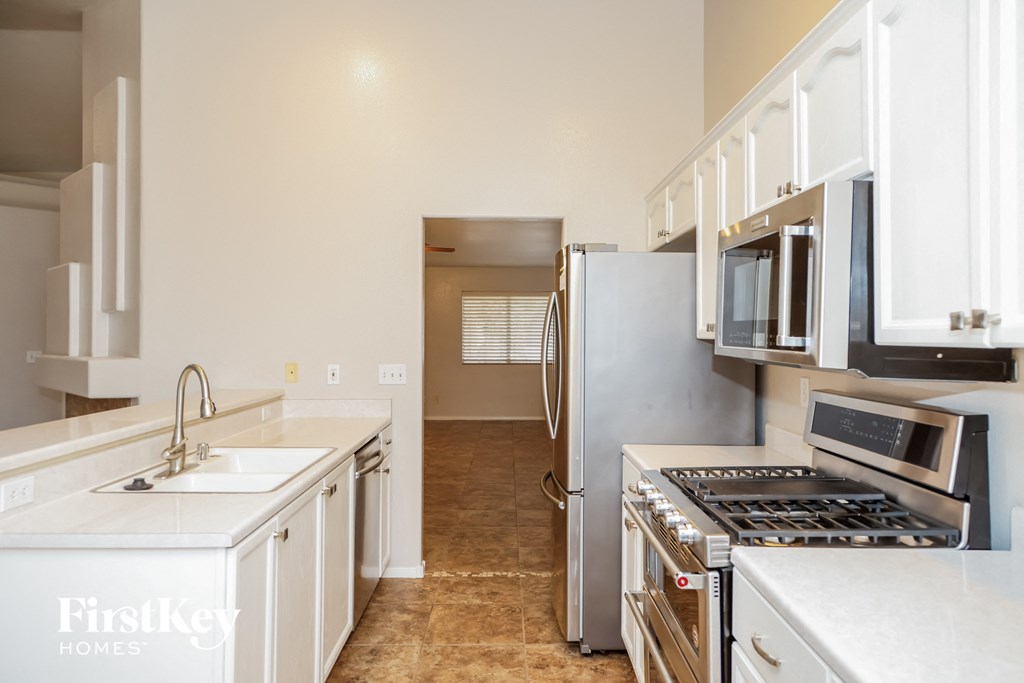 A kitchen with a refrigerator, sink, and stove.