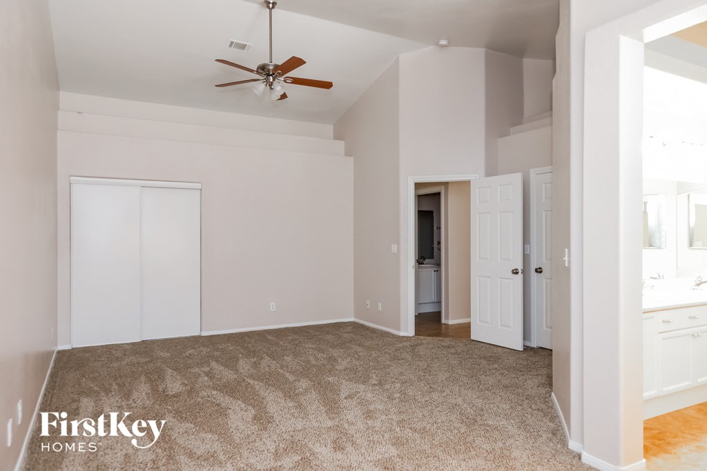 A spacious room with a ceiling fan and a carpeted floor.