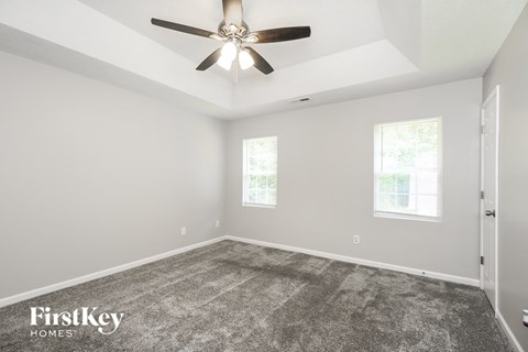 the living room of a new home with carpet and a ceiling fan