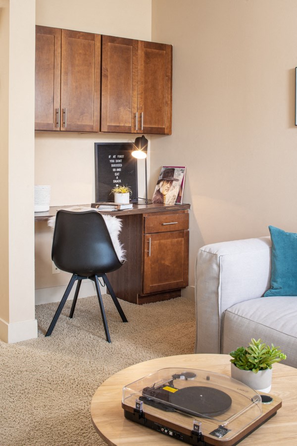 A room with a black chair and a table with a record player on it.