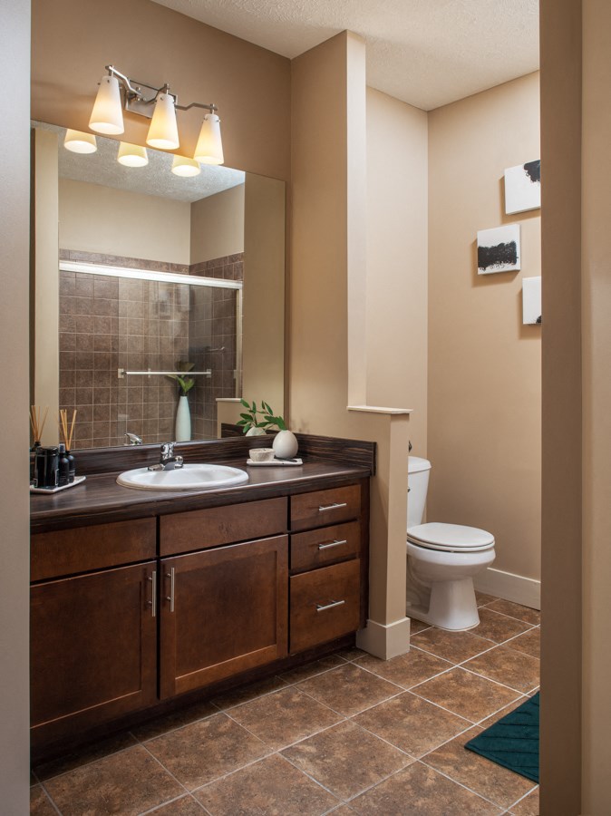 A bathroom with brown cabinets and a white toilet.