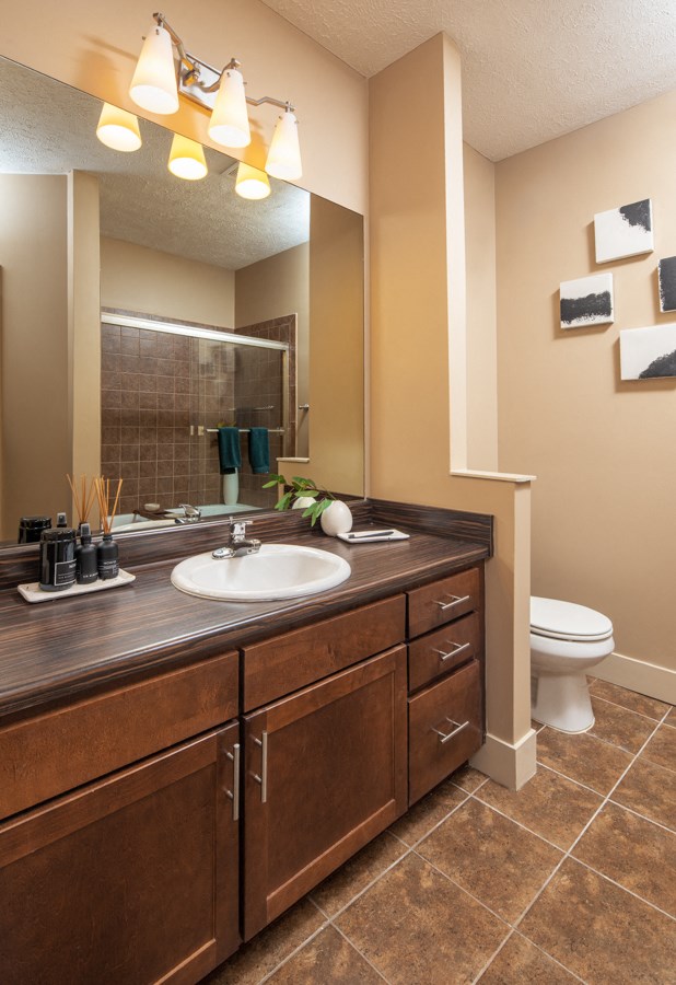 A bathroom with brown wooden cabinets and a white sink.