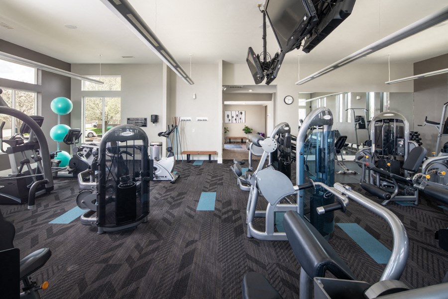 A gym with a variety of equipment including treadmills, weights, and exercise machines.