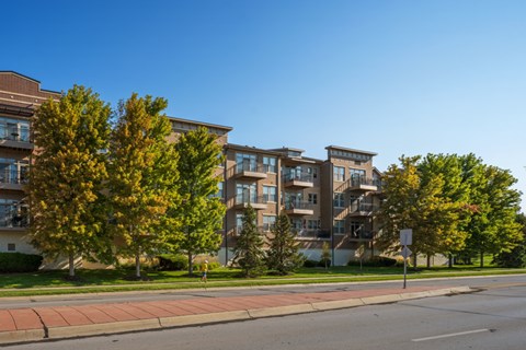 A large apartment building with a red brick sidewalk in front of it.
