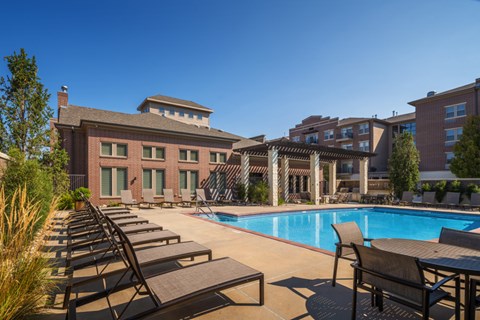 A pool surrounded by lounge chairs and a building in the background.