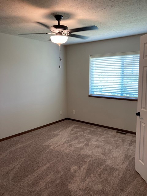 a bedroom with a ceiling fan and a window