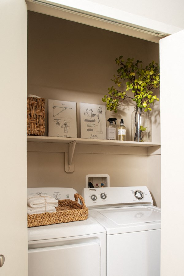 a small laundry room with a white washer and dryer and a shelf above