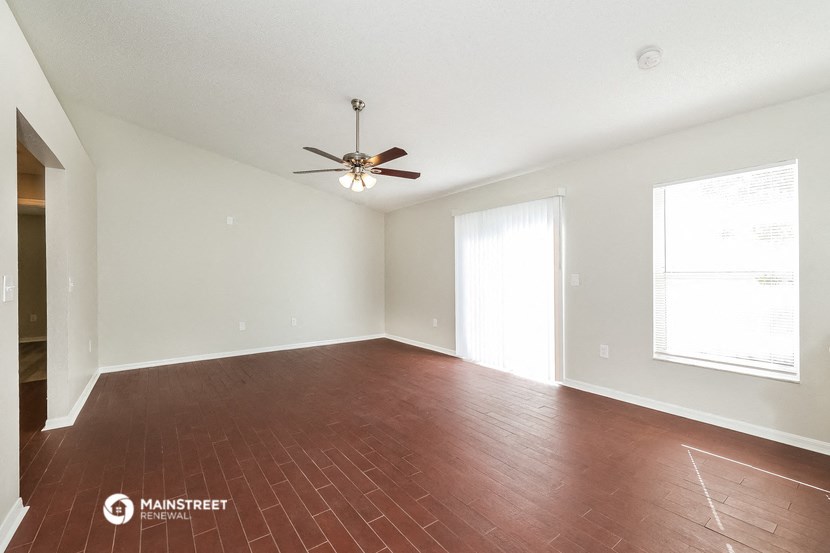 the living room of an empty house with a ceiling fan