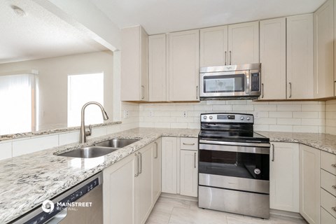 a kitchen with white cabinets and stainless steel appliances