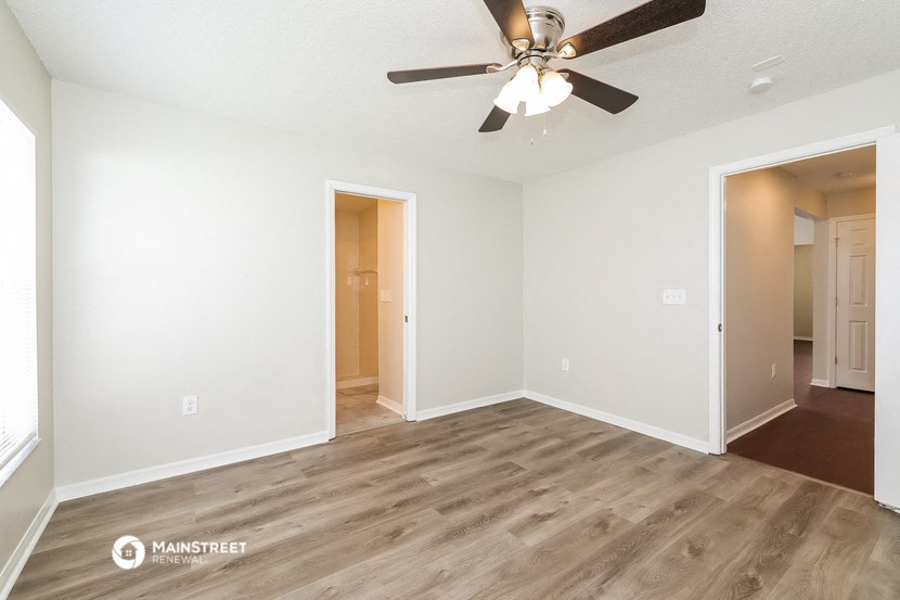 an empty living room with a ceiling fan
