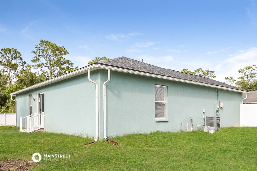 a light blue house with a grassy yard and a blue roof