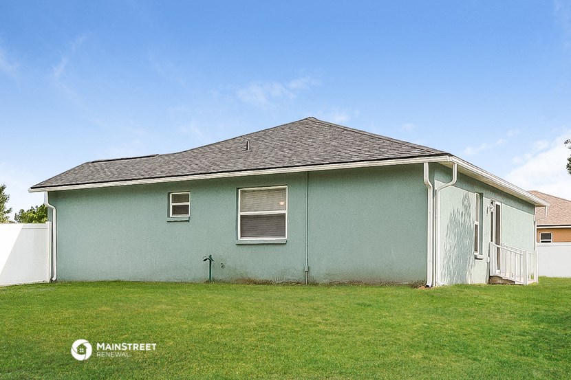 a light blue house with a grassy yard in front of it