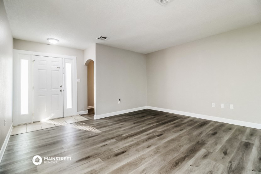 the living room of a new home with wood flooring and a white door
