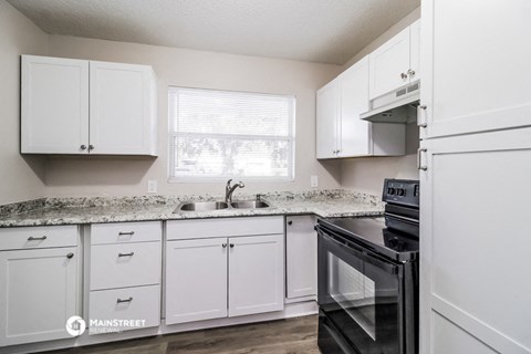 a kitchen with white cabinets and black appliances
