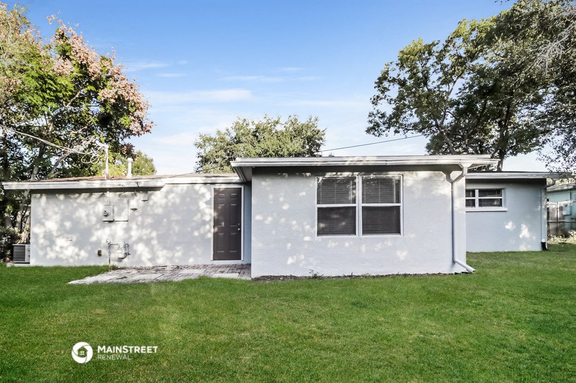 a small white house with a lawn and trees