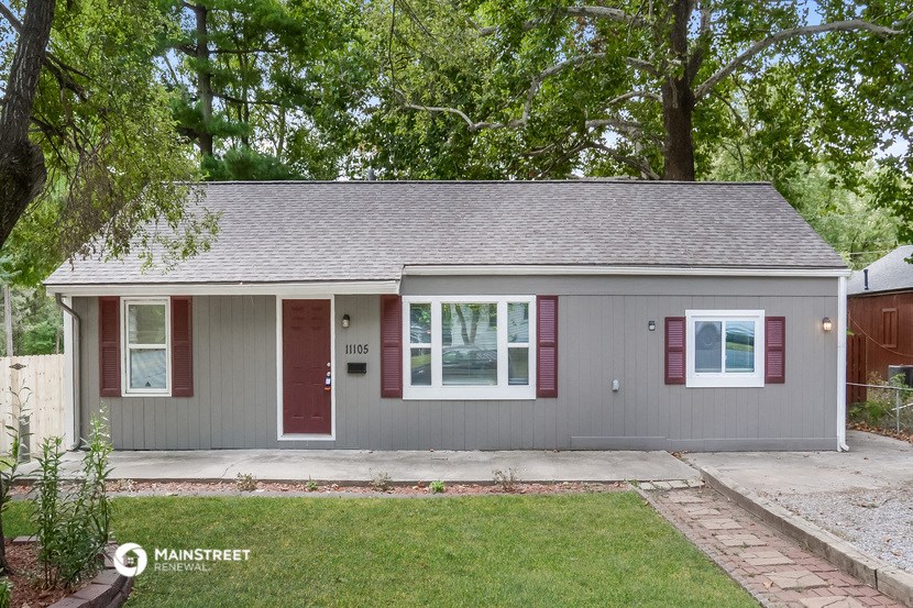 a gray house with red shutters and a lawn