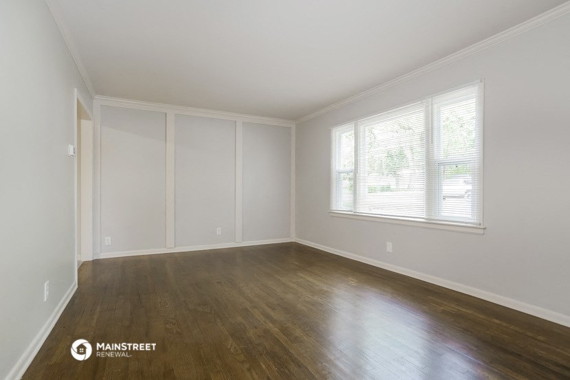 the living room of an empty house with wood floors and a window
