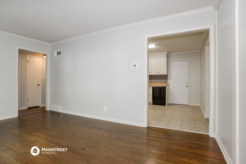 a living room and kitchen with white walls and wood floors