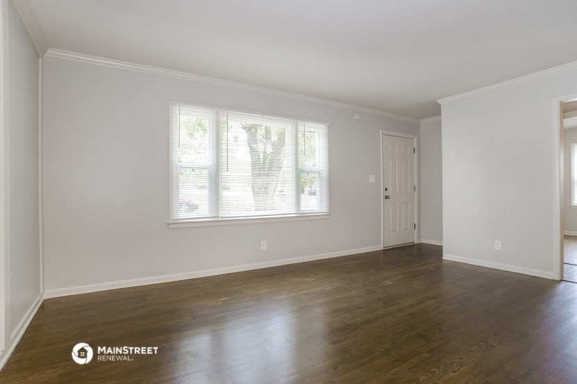 the living room of a house with white walls and wood floors